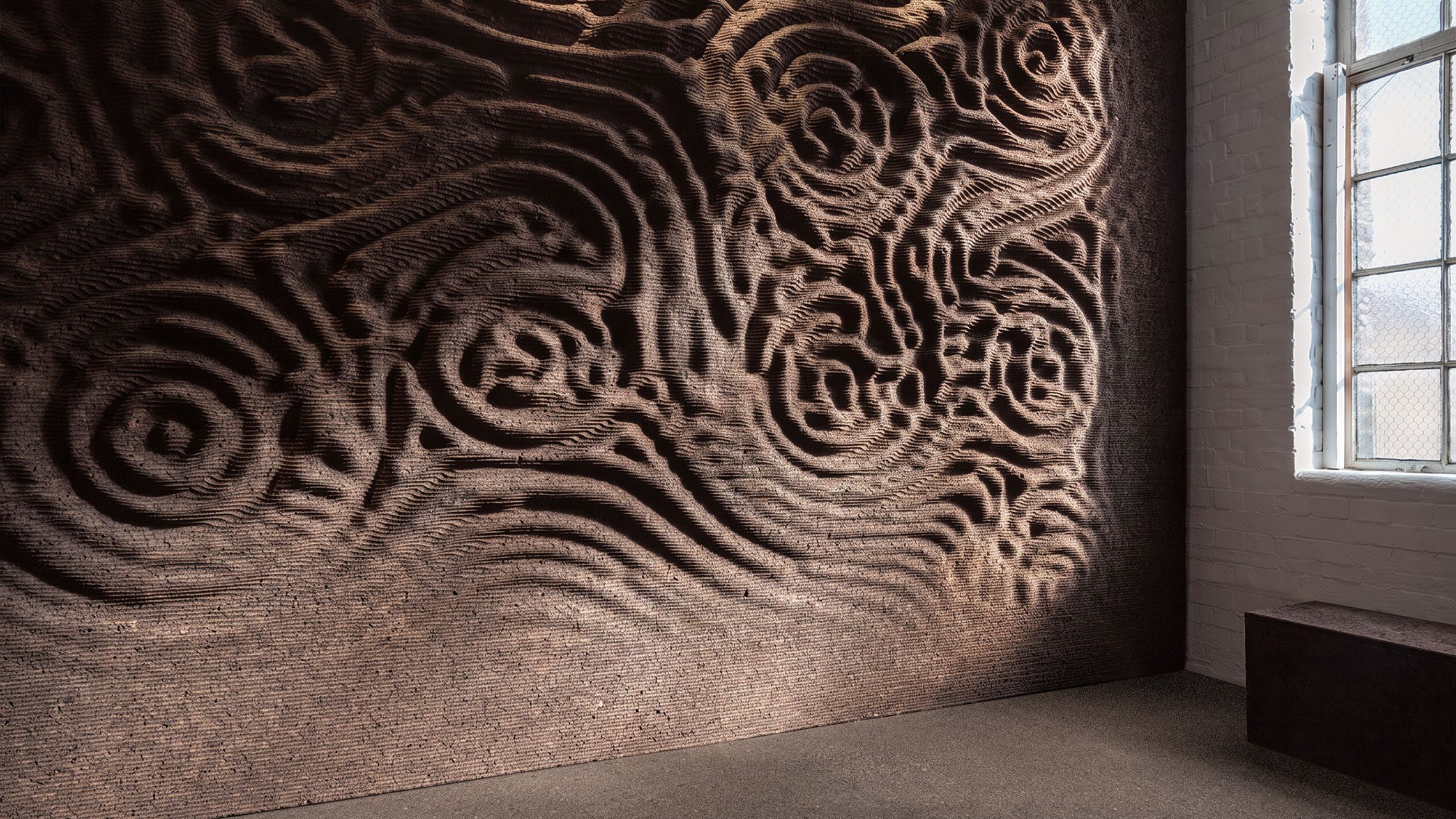GenCork lets an algorithm cut the relief into a black cork wall, image via Dezeen